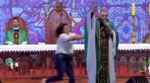 VIDEO // HALUCINANT. Momentul în care un preot este ARUNCAT de pe scenă de o enoriaşă. Ce a scos-o din minţi pe femeie