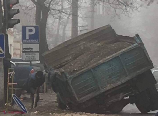 FOTO // Un camion încărcat cu mizerie de pe marginea drumului, rămas blocat cu roțile într-o groapă din asfalt
